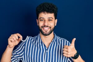 a man is holding invisalign demo and showing thumbs up with a broad smile